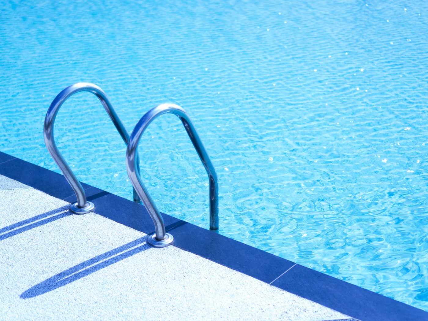A metal ladder leading into a turquoise above-ground swimming pool