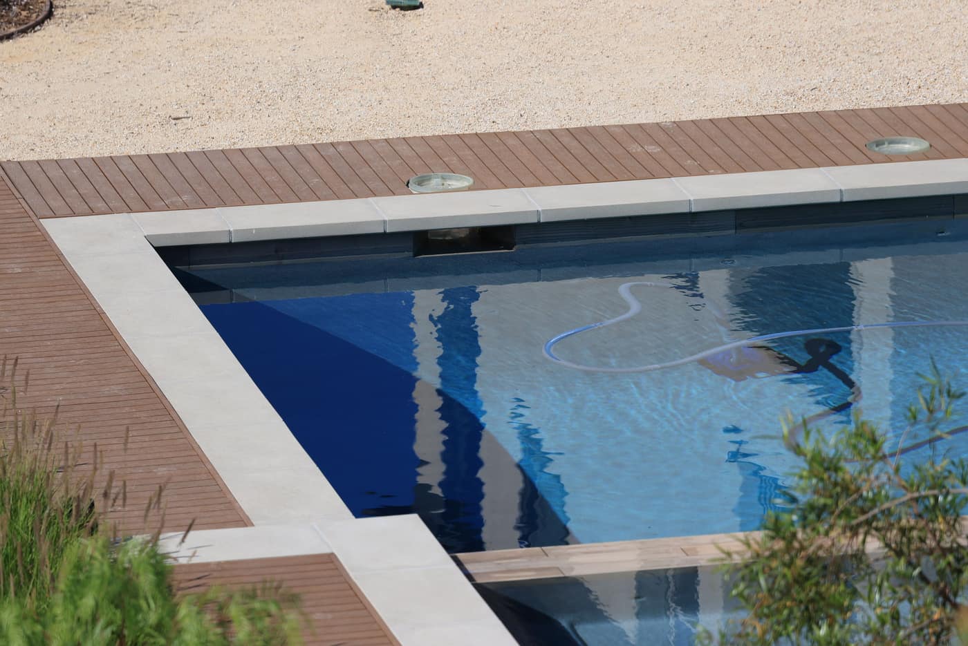 A robotic pool cleaner working across the floor of a blue swimming pool