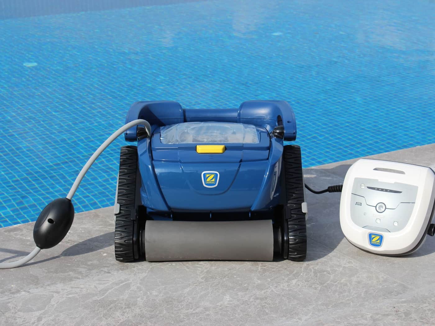 A robotic pool cleaner resting at the edge of a swimming pool