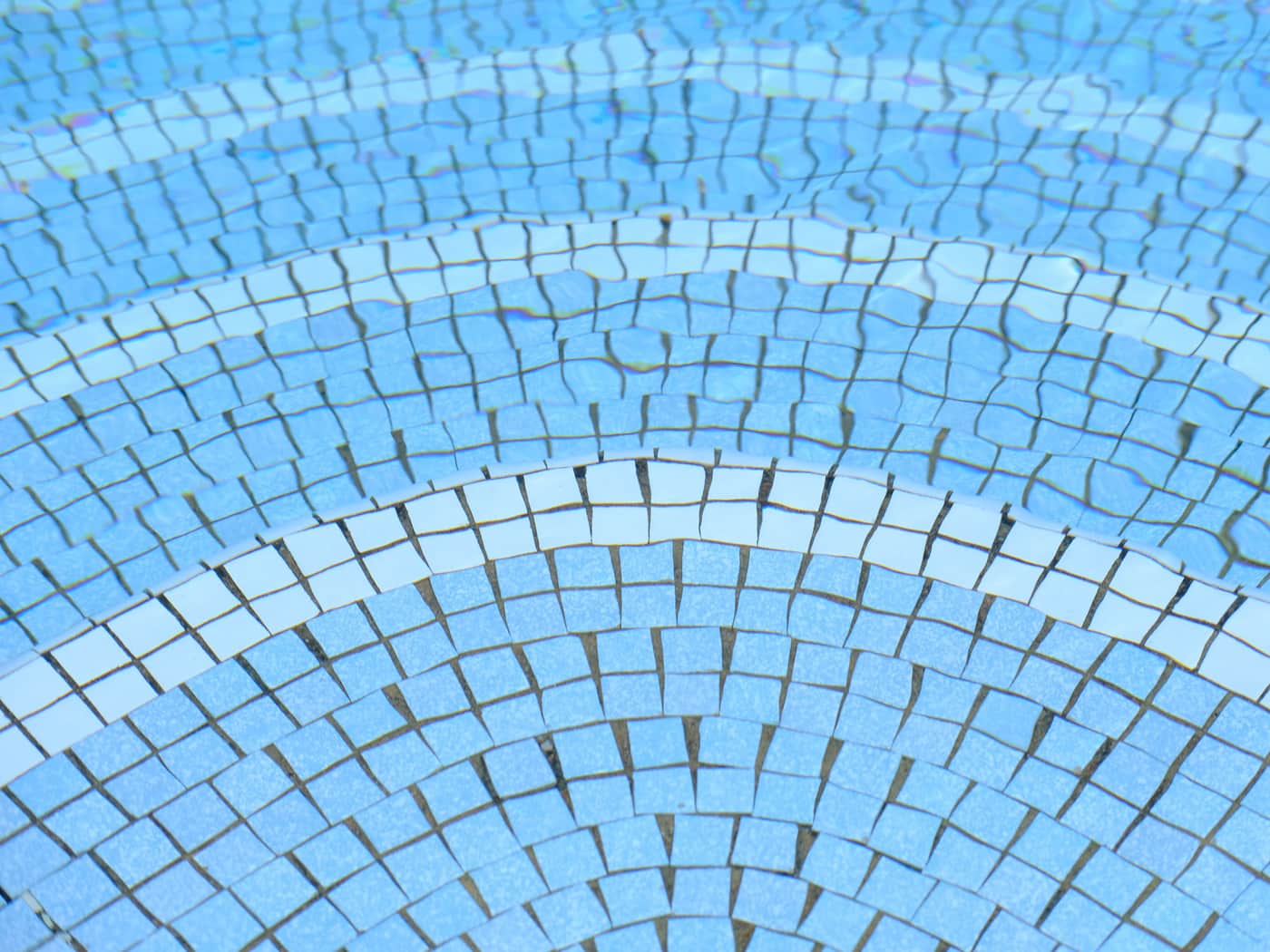 Blue and white mosaic tiles under clear pool water