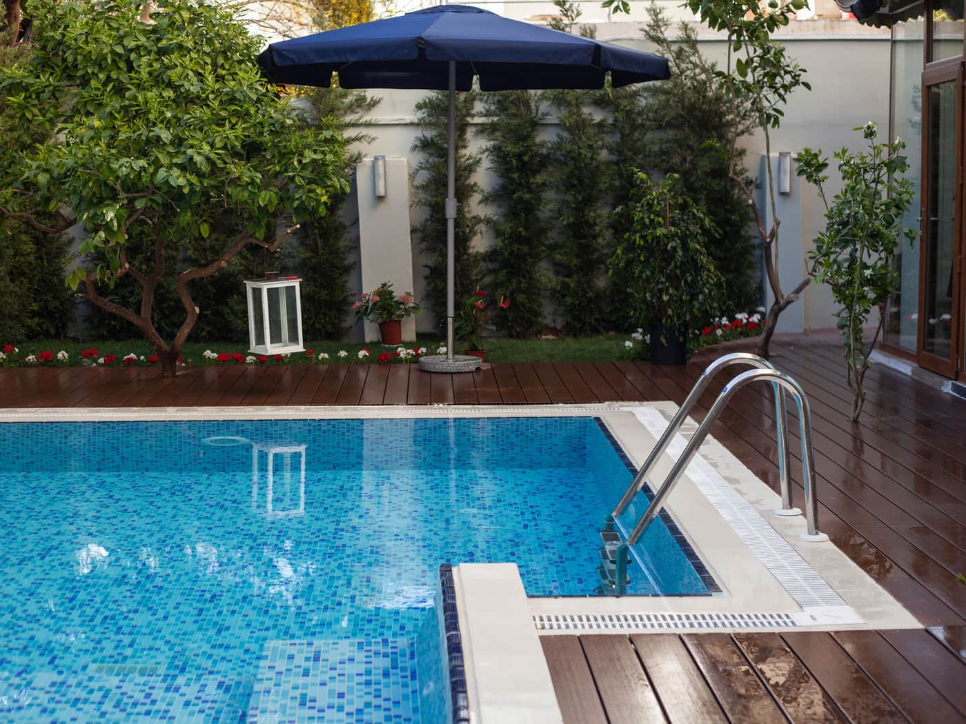 A backyard swimming pool beside a garden and wooden deck