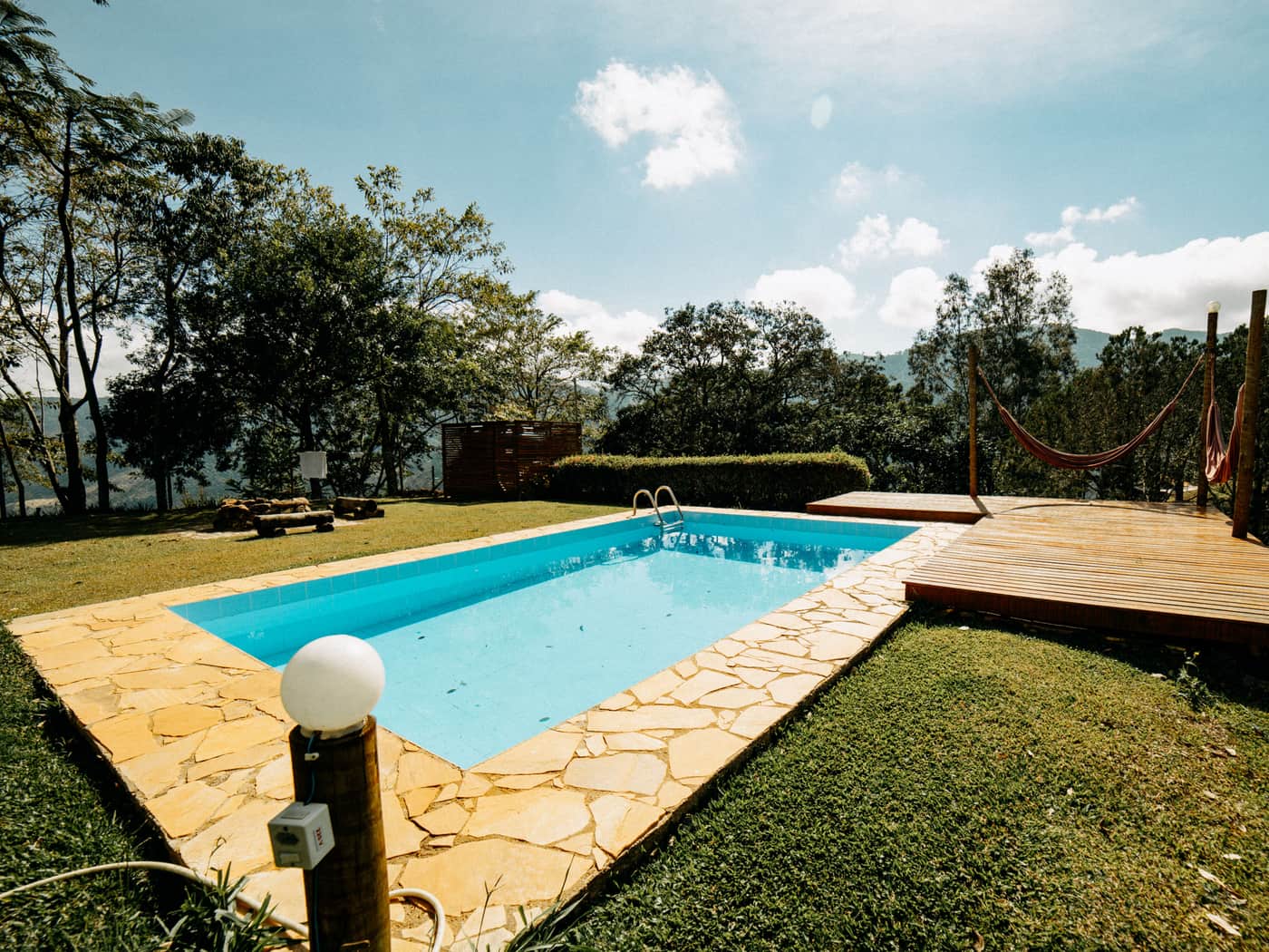 An outdoor pool with a wooden deck surrounded by greenery