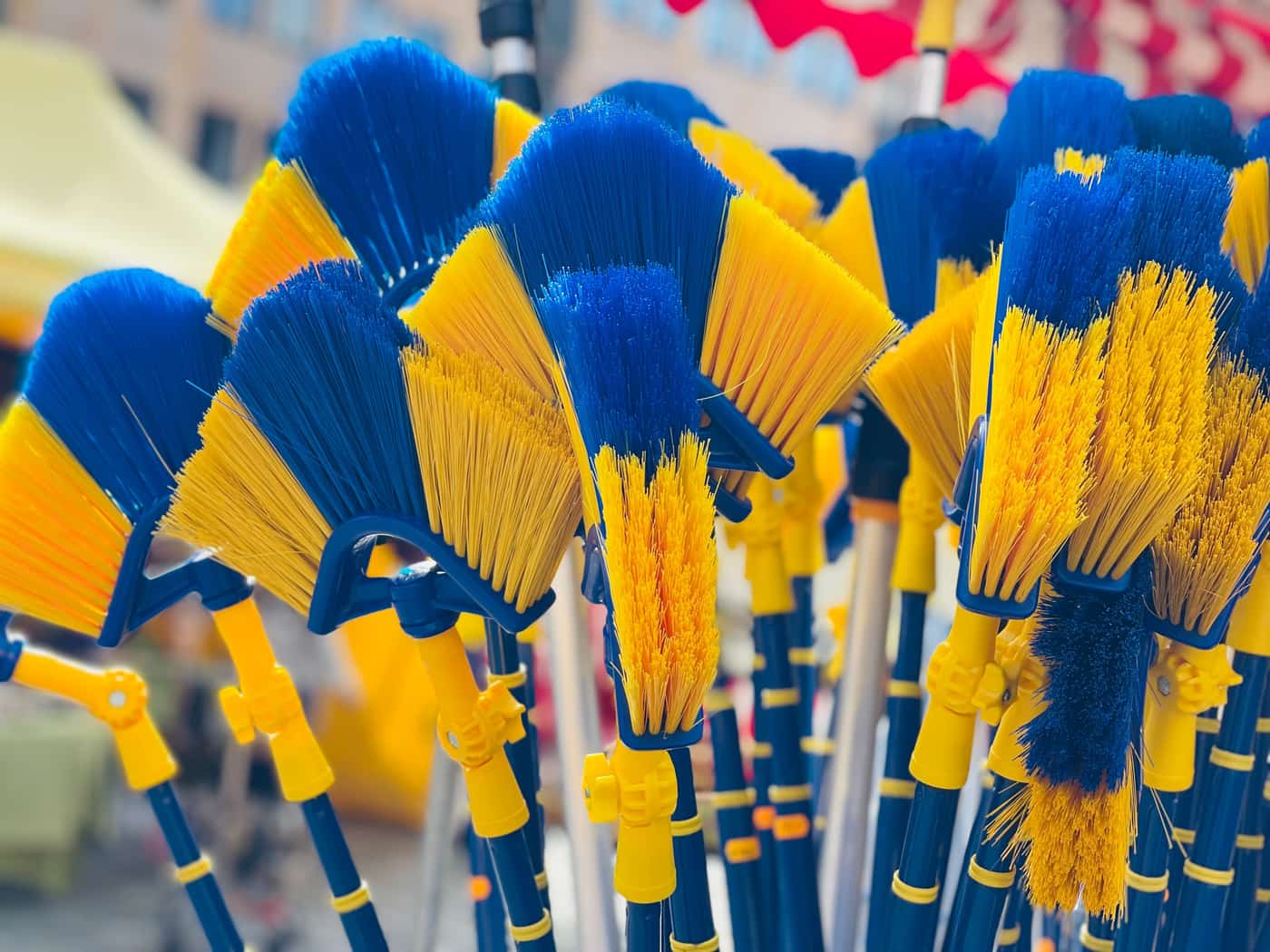 Pool cleaning tools including a brush, net and pole beside a pool
