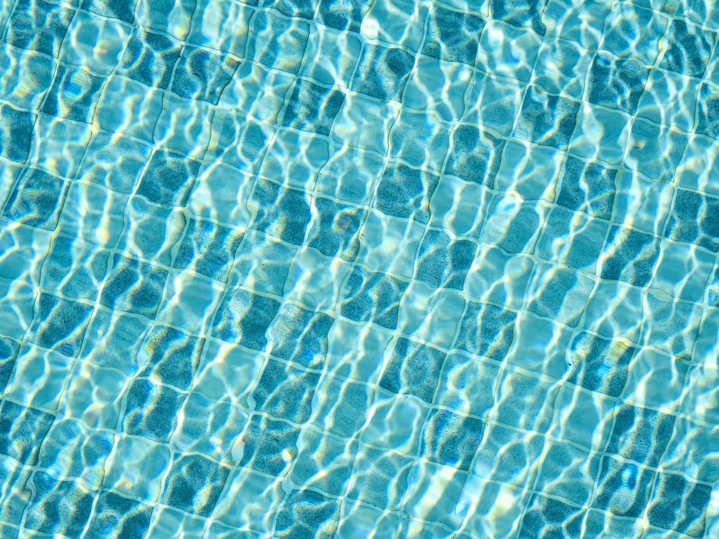 Sunlight glittering over mosaic tiles on a swimming pool floor