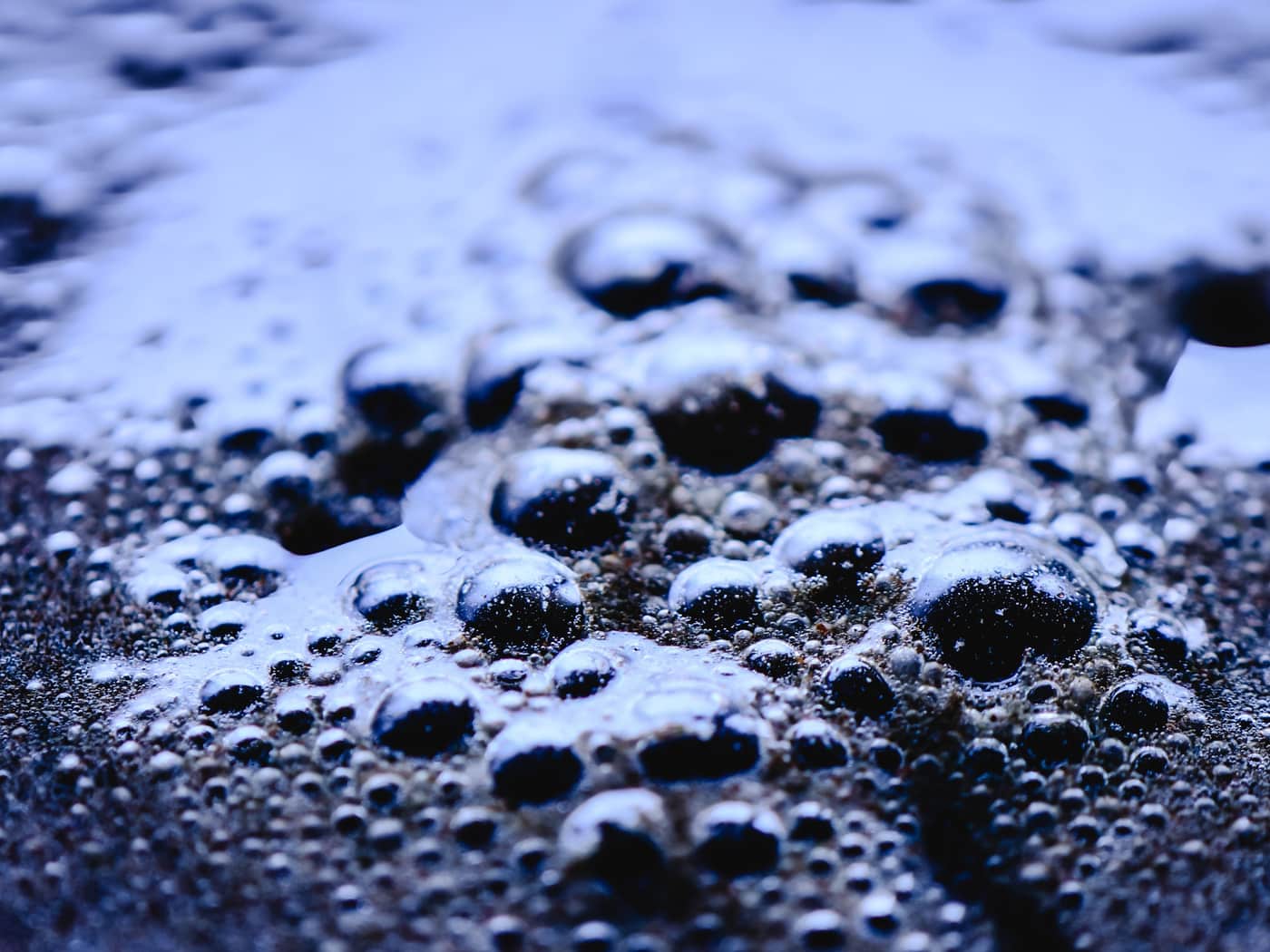 Close-up of foam and fine bubbles on a blue water surface