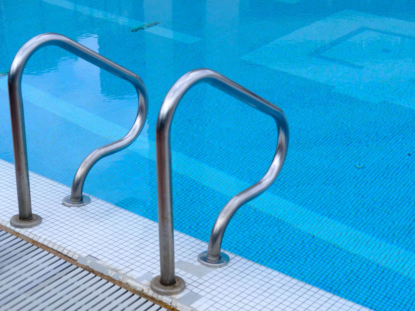Stainless steel handrails at the edge of a tiled swimming pool