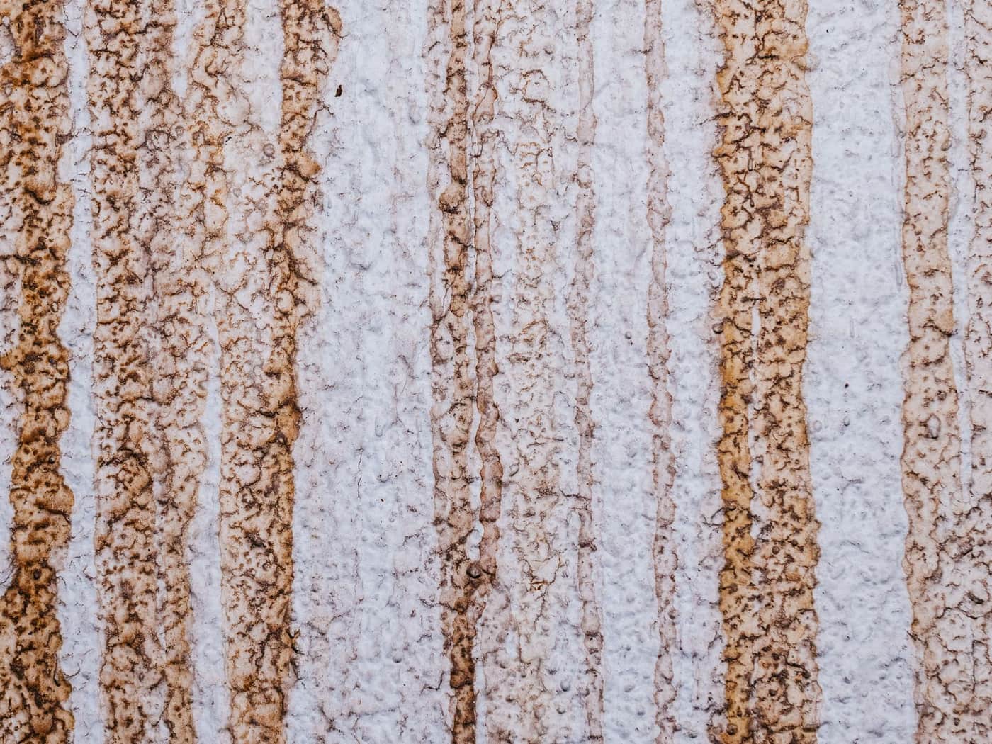 Brown rust-colored stains streaking down a textured wall