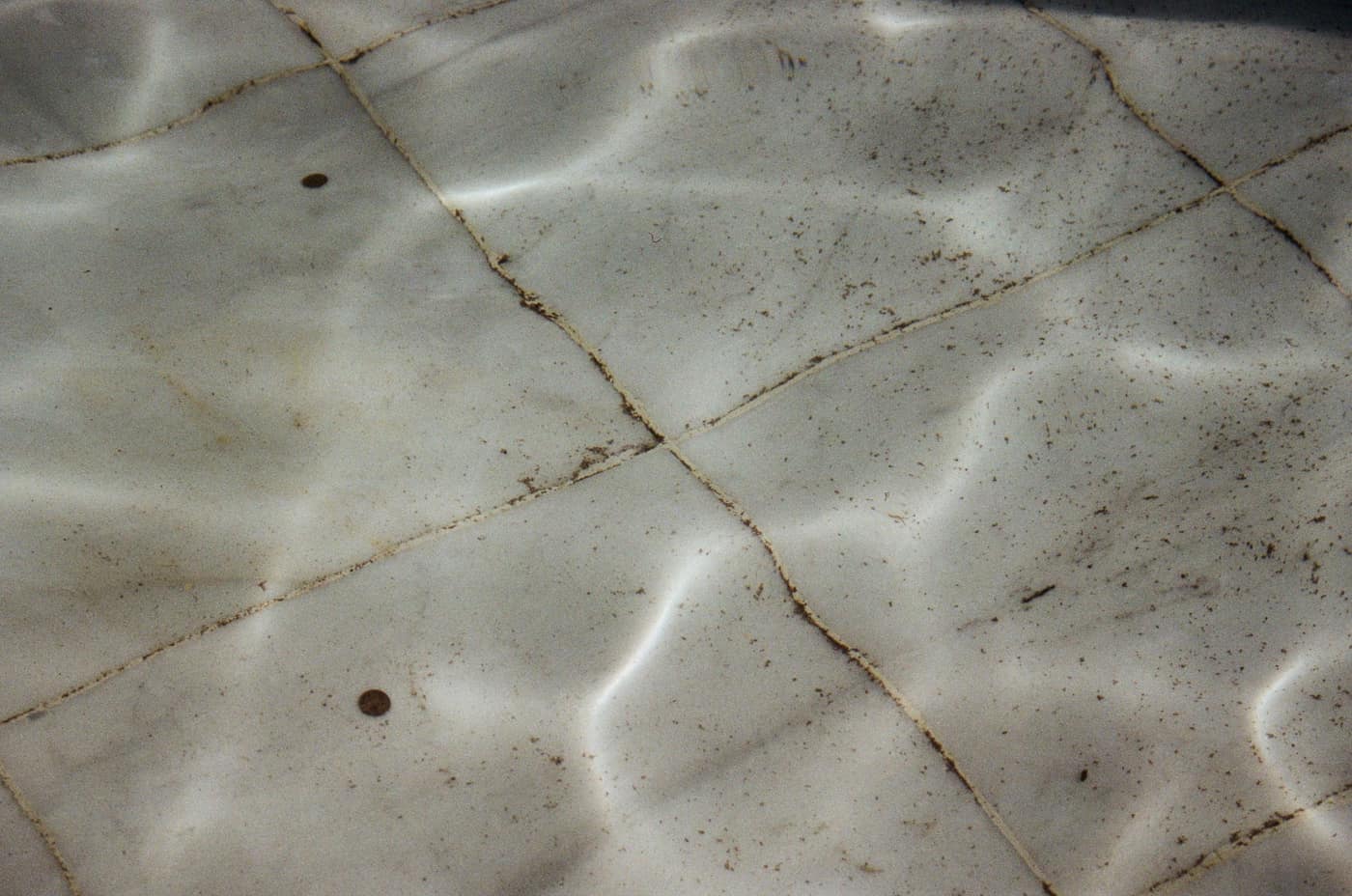 Yellow-tan sediment settled in a shaded corner of a swimming pool