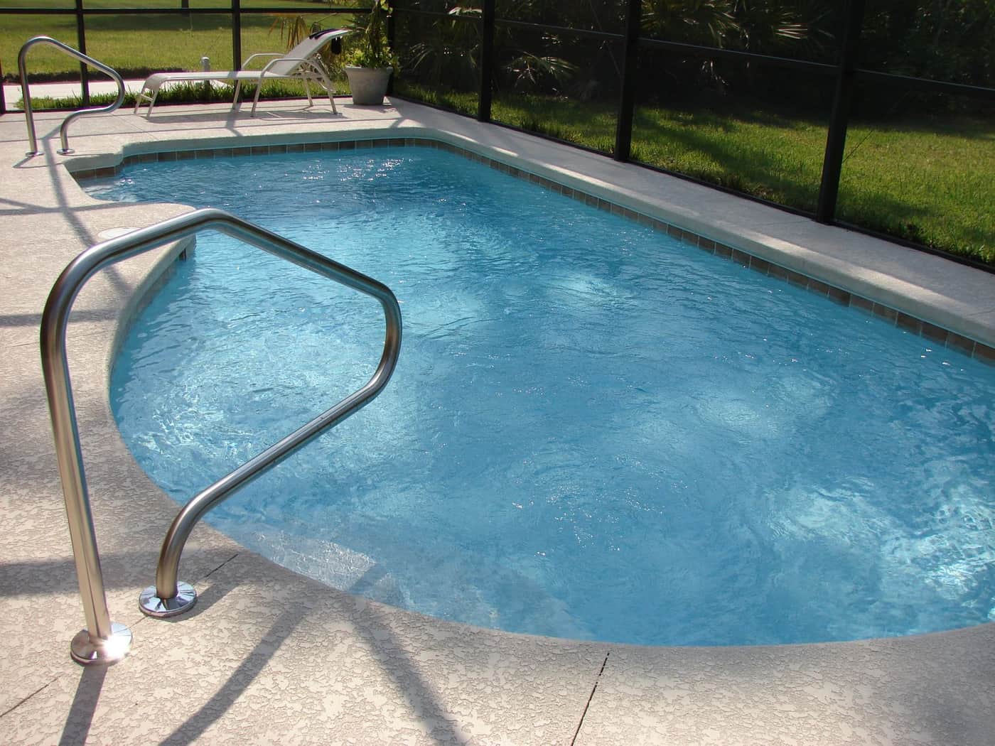 A clean in-ground swimming pool in a sunny backyard