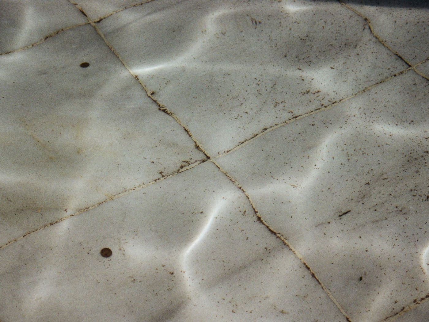 Dirty textured tiles on the floor and wall of a swimming pool, seen underwater