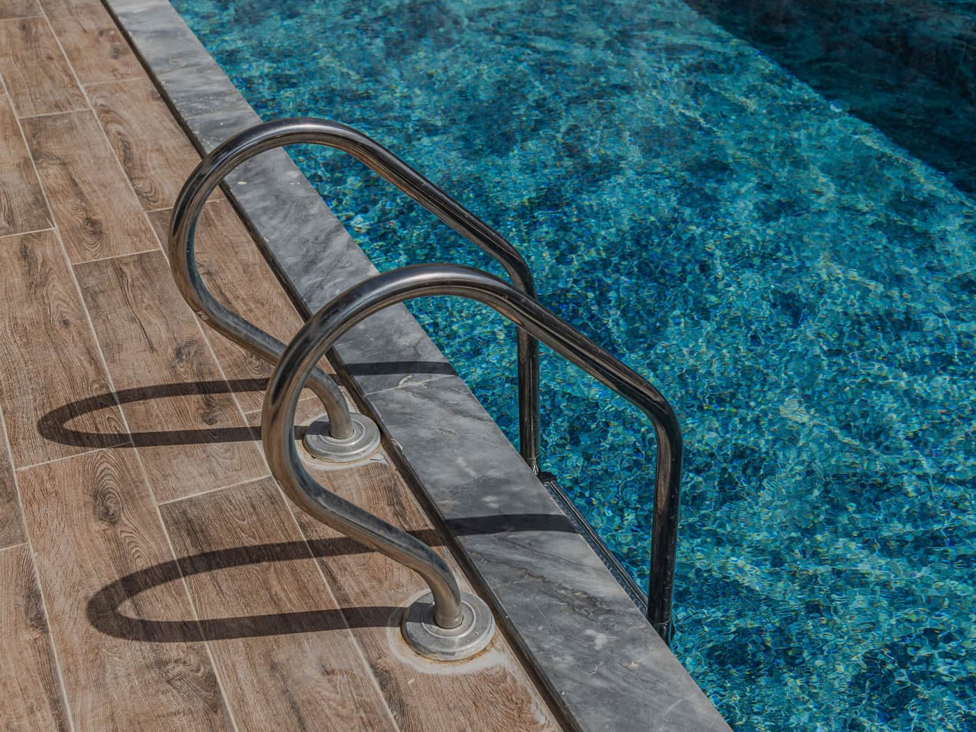 Pool ladder and deck beside clear blue water