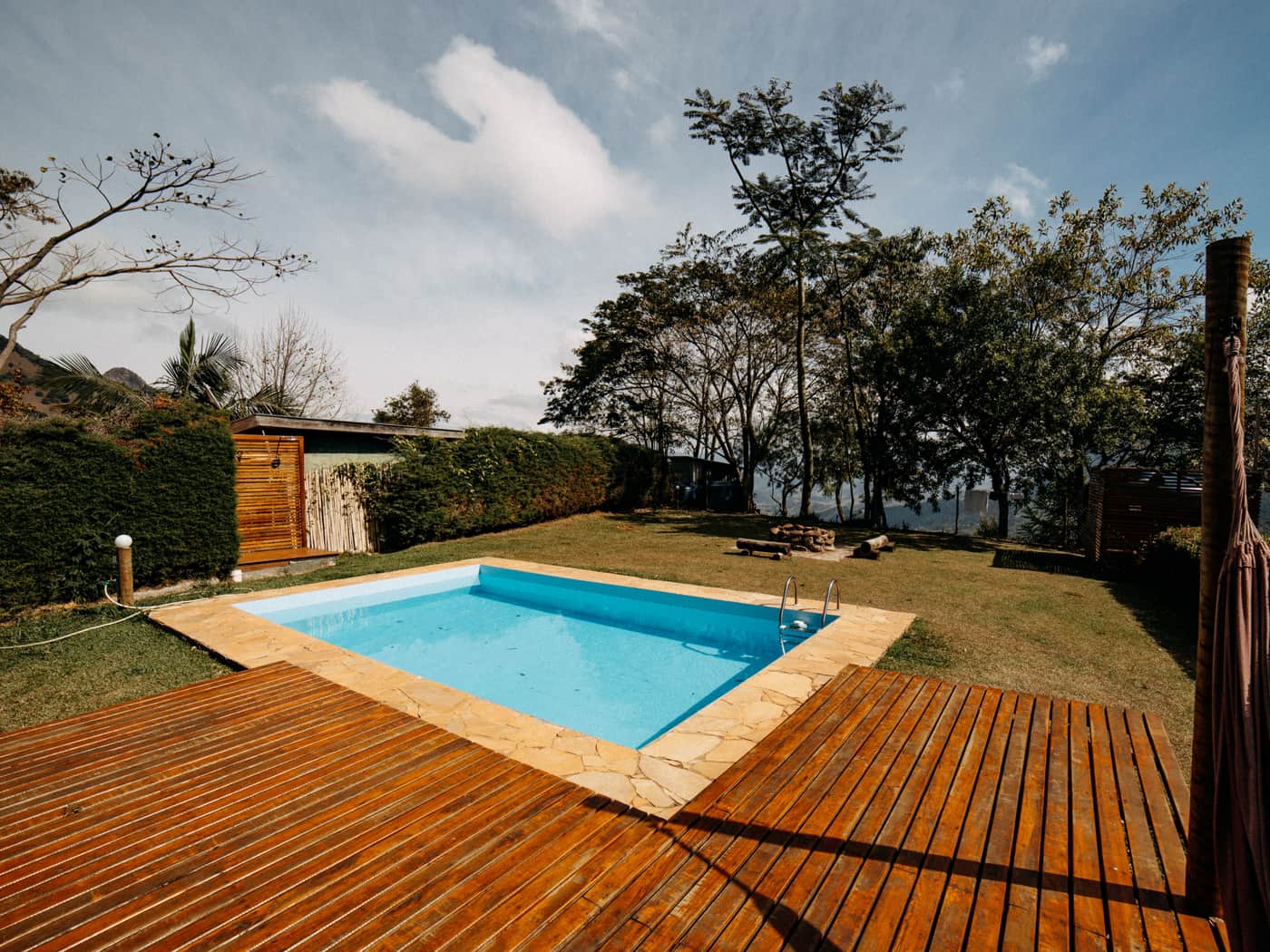 An outdoor pool with wooden decking and surrounding greenery