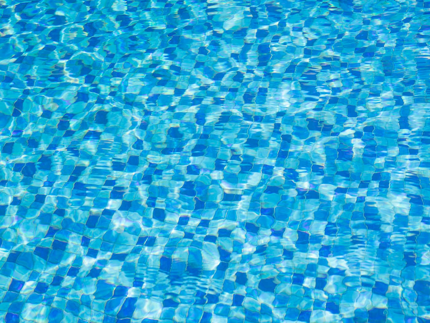 Tiles seen through clear rippling pool water from above