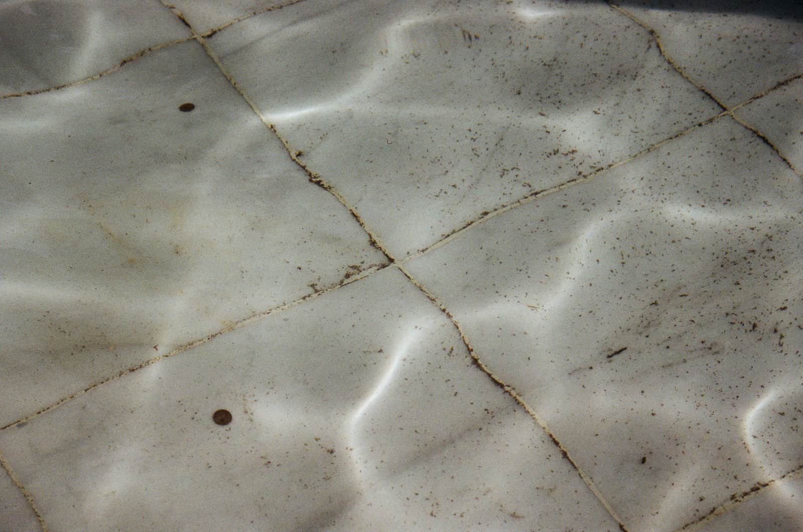 A robotic pool cleaner on the floor of an inground pool