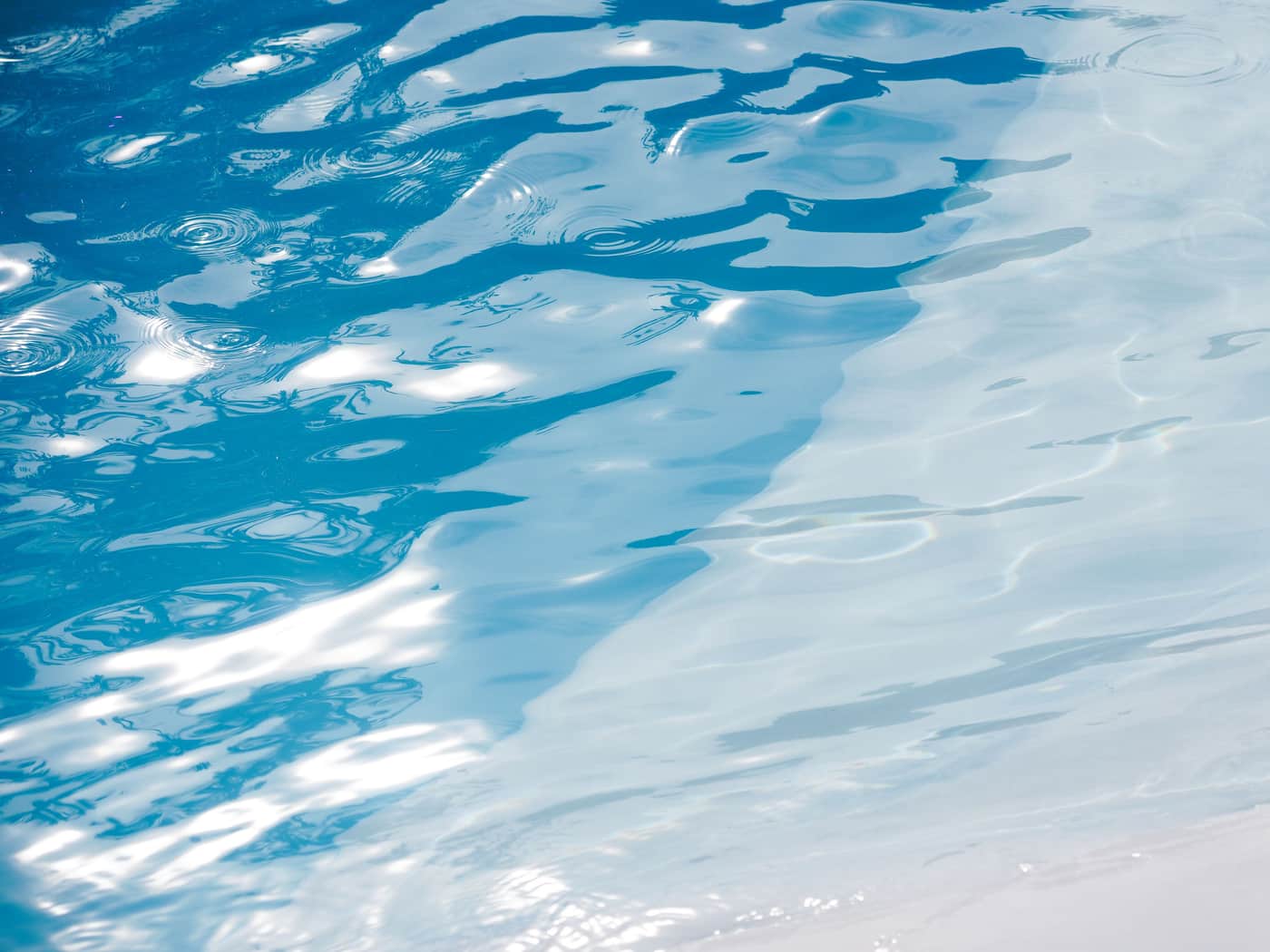 Sunlit ripples across a blue swimming pool