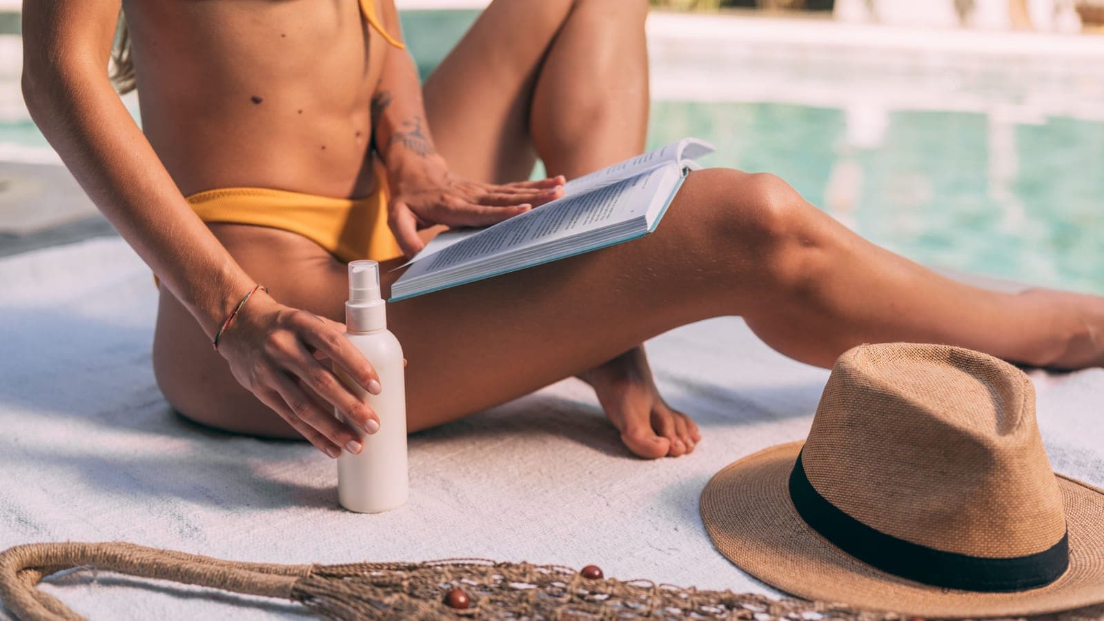 Sunscreen bottle beside a swimming pool on a summer day