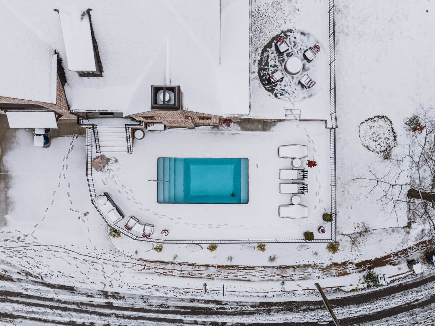 A swimming pool covered for winter beside a bare tree
